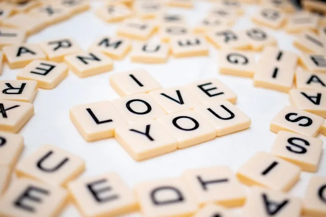 Macro photo of I love you spelt in letter tiles on a white background, surrounded by scattered files. 100 Ways to Say I Love You
